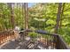 Elevated back deck with outdoor dining set, grill, and serene views of the surrounding wooded landscape at 112 Fairford Dr, Holly Springs, NC 27540