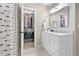 Stylish bathroom featuring a modern vanity, mirror, and an adjacent walk-in closet for ample storage at 112 Fairford Dr, Holly Springs, NC 27540