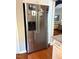 Close-up of stainless refrigerator, white cabinets, and hardwood floors at 112 Fairford Dr, Holly Springs, NC 27540