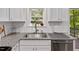 Close-up of a kitchen sink and countertop with white cabinets, granite counters, and subway tile backsplash at 112 Fairford Dr, Holly Springs, NC 27540