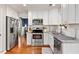 Bright kitchen with white cabinets, stainless steel appliances, granite countertops, and hardwood flooring at 112 Fairford Dr, Holly Springs, NC 27540