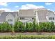 Gray homes as seen from a pond with a retaining wall and lush greenery at 113 Mazarin Ln, Cary, NC 27519