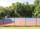 Outdoor tennis court with a blue and red surface, surrounded by a fence and mature trees at 114 Oxpens Rd, Cary, NC 27513