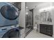 Contemporary bathroom and laundry featuring a sleek shower, stackable washer/dryer, and vanity at 1208 Hunting Ridge Rd, Raleigh, NC 27615