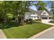 Beautiful white home with a well-manicured lawn, mature trees, and a circular driveway at 1208 Hunting Ridge Rd, Raleigh, NC 27615