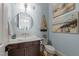 Stylish powder room with unique vanity, nautical decor, and beach-themed artwork at 1208 Hunting Ridge Rd, Raleigh, NC 27615