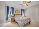 Bedroom featuring large windows dressed with blue curtains, a bed with blue floral bedding, and a ceiling fan at 12140 Pawleys Mill Cir, Raleigh, NC 27614