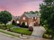 Well-maintained brick home featuring two-car garage and landscaped grounds at dusk at 12140 Pawleys Mill Cir, Raleigh, NC 27614
