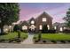 Charming brick home featuring manicured lawn, mature trees and inviting front entrance at dusk at 12140 Pawleys Mill Cir, Raleigh, NC 27614