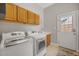 Well-lit laundry room features a washer and dryer, wooden cabinets, tile flooring, and a sink for added convenience at 12140 Pawleys Mill Cir, Raleigh, NC 27614