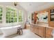 Bright bathroom featuring a soaking tub, natural wood cabinets, and ample natural light at 131 Lavinia Ln, Chapel Hill, NC 27516