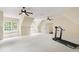 Large bonus room with a treadmill, natural light, and multiple ceiling fans at 131 Lavinia Ln, Chapel Hill, NC 27516