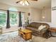 Comfortable living room with a ceiling fan, neutral walls, hardwood floors, and large windows and leather seating at 1509 Elkpark Dr, Raleigh, NC 27610
