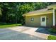 Side door and parking area of home, surrounded by grassy areas and mature trees at 1511 Hatch Rd, Chapel Hill, NC 27516
