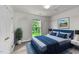 Cozy bedroom featuring a blue bed frame, stylish bedding, and a window with a view of lush greenery at 1725 E Honey Springs Ave, Fuquay Varina, NC 27526