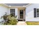 Close-up of the front door with sidelight, black shutters, surrounded by lush plants adding to curb appeal at 1725 E Honey Springs Ave, Fuquay Varina, NC 27526
