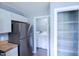 Efficient laundry area with stainless steel refrigerator, washer, dryer, and organized shelving for storage at 1806 Stroll Cir, Fuquay Varina, NC 27526