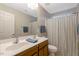 Bathroom with double vanity and framed mirror with wood cabinets and a shower with a blue stripped shower curtain at 201 Forbes Rd, Wake Forest, NC 27587