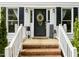Charming front porch with brick steps, decorative wreath, and welcome decor creating a warm and inviting entryway at 21 Cedar Hill Dr, Durham, NC 27713