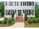 Inviting home entrance with brick steps and landscaped garden beds beneath white framed windows and black shutters at 21 Cedar Hill Dr, Durham, NC 27713