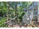 Backyard view of the house with a gray deck, screened porch, and steps leading to brick path at 2125 Oakcrest Ct, Raleigh, NC 27612