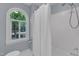 Bathroom featuring a tub with shower and an arched window at 2125 Oakcrest Ct, Raleigh, NC 27612