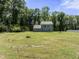 Expansive backyard with a green lawn and mature trees surrounding the property, with the home visible at 218 Mason Rd, Durham, NC 27712