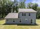 Exterior of a home with gray siding, a dark roof, and windows, plus a door opening onto the yard at 218 Mason Rd, Durham, NC 27712