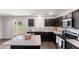 An open kitchen with an island, stainless steel appliances, modern fixtures, and dark wood cabinetry at 218 Mason Rd, Durham, NC 27712