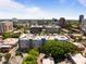 A birds eye view shows an apartment building surrounded by trees and the city skyline on a sunny day at 222 Glenwood Ave # 714, Raleigh, NC 27603