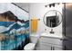 Bright bathroom features a mountain-themed shower curtain, round mirror, and white vanity at 2805 Fayetteville St, Durham, NC 27707
