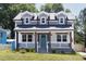 Charming two-story home with dormer windows, a covered porch, and a bright teal-colored front door at 2805 Fayetteville St, Durham, NC 27707