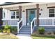 Inviting front porch with white railings, brown columns, and a vibrant teal front door at 2805 Fayetteville St, Durham, NC 27707