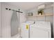 Functional laundry room with washer, dryer, shelving, and ironing board at 309 S Haywood St St, Raleigh, NC 27601