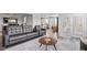 Open-concept living room featuring a gray leather sofa, fireplace, large windows and adjacent dining and kitchen areas at 337 Brinkley Cir, Mebane, NC 27302
