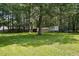 A wide backyard with a shed, a covered structure on stilts, lush lawn and mature trees at 353 Spearhead Pl, Clayton, NC 27520