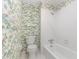 Full bathroom featuring a tub and shower with a vintage lilypad wallpaper and white tiling at 4030 King Charles Rd, Durham, NC 27707
