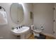 Bright bathroom features a pedestal sink with a round mirror, wooden floors, and gray walls at 441 Heritage Village Ln, Apex, NC 27502