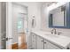 Bright bathroom with white vanity, neutral walls, a framed mirror, and open doorway at 4906 Lakemont Dr, Raleigh, NC 27609