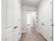 Hallway featuring wood-look tile floors, multiple storage closets, and bright white walls and doors at 4906 Lakemont Dr, Raleigh, NC 27609