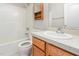 A bathroom with a white shower/tub combo, toilet, wood cabinets, stone countertop, and a sink at 503 Kinship Ln, Apex, NC 27502