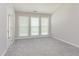 A bedroom with three windows, gray carpet, and a white door at 503 Kinship Ln, Apex, NC 27502