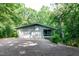 Exterior featuring an attached two-car garage and a screened-in porch, surrounded by lush trees at 5213 Tomahawk Trl, Raleigh, NC 27610