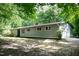 The exterior of a single-story home featuring a low-pitched roof and horizontal siding in a wooded setting at 5213 Tomahawk Trl, Raleigh, NC 27610