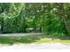 Serene view of property frontage through a dense canopy of trees at 5213 Tomahawk Trl, Raleigh, NC 27610