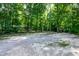 Wide gravel parking area offering generous space, surrounded by lush trees, with a home in the background at 5213 Tomahawk Trl, Raleigh, NC 27610