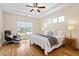 Bright primary bedroom with hardwood floors, a ceiling fan, and large windows for natural light at 68 Tanners Way, Clayton, NC 27527
