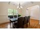 Dining room with hardwood floors, modern chandelier, large window, and an arched entryway at 68 Tanners Way, Clayton, NC 27527