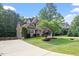 Beautiful two-story home with lush landscaping, mature trees, and a winding driveway on a sunny day at 68 Tanners Way, Clayton, NC 27527
