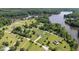 Expansive aerial view showcasing lakefront homes nestled amongst verdant trees and open green spaces under a clear sky at 724 Harolds Northfield Dr, Cedar Grove, NC 27231